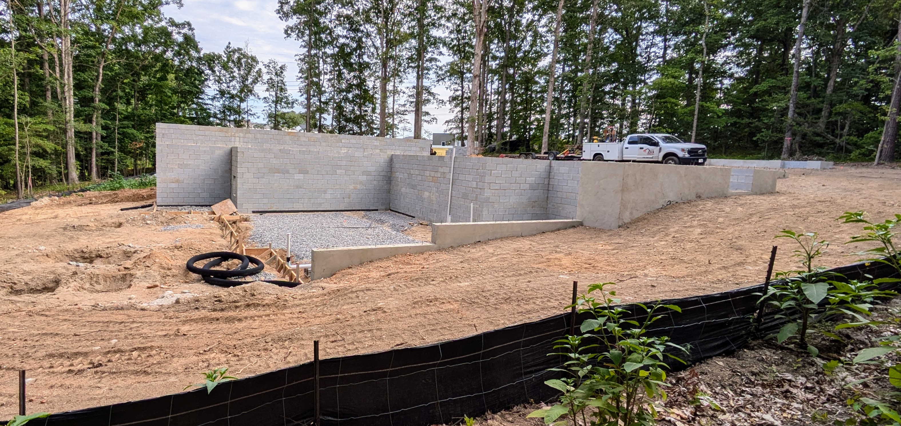 Block foundation of a walkout basement and first story with pickup and trees in the background. 