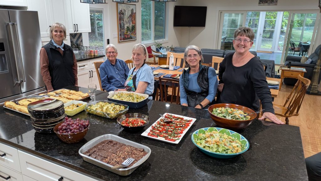 People gathered around a kitchen island filled with various dishes of food.